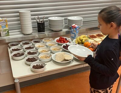 Kind mit Teller in der Hand vor einem reichhaltigen Frühstücksbuffet